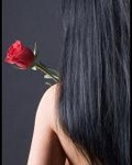 Брюнетка с длинными волосами стоит спиной и держит розу