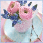 Букет розовых и голубых цветов в маленькой вазе на блюдце