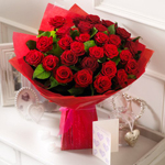 Букет красных роз стоит на тумбочке с открыткой