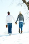 Влюбленная пара держась за руки идет по снегу