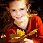 Улыбающаяся девочка с желтыми листьями в руках