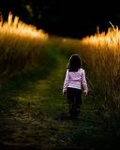 Девочка идет по дороге вдоль пшеничного поля