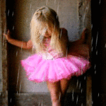 Девочка - балерина в розовой пачке стоит, держась за стен...