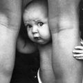 Ребенок выглядывает из-за маминой ноги
