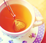 Металлическое сердечко в чашке с чаем на блюдце с цветами
