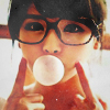 Азиатка в очках надувает пузырь из жвачки