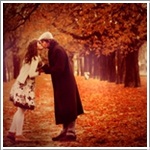Мужчина целует женщину на аллее осеннего парка