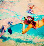 Девушка в венке целует дельфина