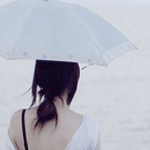 Девочка с зонтом стоит у моря