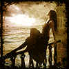 Девушка сидит на парапете и смотрит на закат над морем