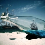 Парусник на море виден через бутылку на берегу