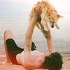 Парень играется со своей собакой, лежа на песке морского ...