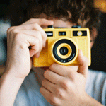 Парень с желтым фотоаппаратом в руках