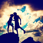 Парень с девушкой целуется на фоне неба стоя на камне