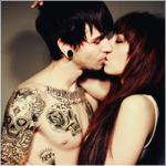 Парень с татуировками целует девушку