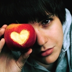 Красивый парень держит в руке яблоко с вырезанным сердечком