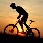 Парень на велосипеде на фоне заката