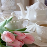 Букет розовых тюльпанов лежащий рядом с белым чайным серв...