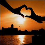  <b>Влюблённые</b> сложили руки сердечком на фоне заката 