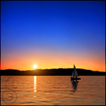 Яхта, плывущая по озеру, на фоне красивого заката солнца ...