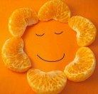 Дольки мандарина на оранжевой бумаге с нарисованной улыба...