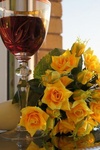 Букет желтых роз лежит возле бокала с вином