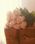 Букет красивых роз лежит на чемодане