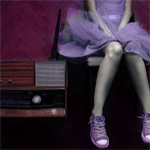 Девочка в фиолетовом платье и кедах сидит на стуле рядом ...