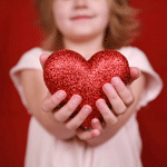  Девочка держит красное <b>сердечко</b> в руках 