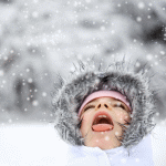 Ребенок ловит языком снег