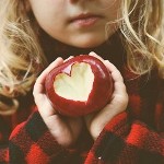  Девочка держит яблоко с <b>вырезанным</b> сердечком 
