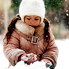 Девочка в белой шапке играет со снегом