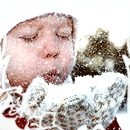 Ребёнок дует на снег на варежках