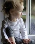 Малыш сидит на подоконнике и одиноко смотри в окно