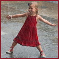Девочка в красном платье улыбается под дождем