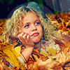 Девочка сидит в куче листьев