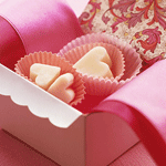 Конфеты в виде сердец лежат в розовой коробке