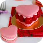 Розовое пирожное в виде сердца с малиной на блюдце