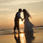 Поцелуй невесты на берегу моря на фоне заходящего солнца