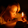 Ребёнок задумчиво смотрит на свечу