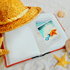 Шляпка, ракушка и книга на белом песке