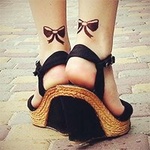 Женские ножки с татуировкой в виде бантиков в черных босо...