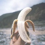Банан в руке на фоне горного пейзажа